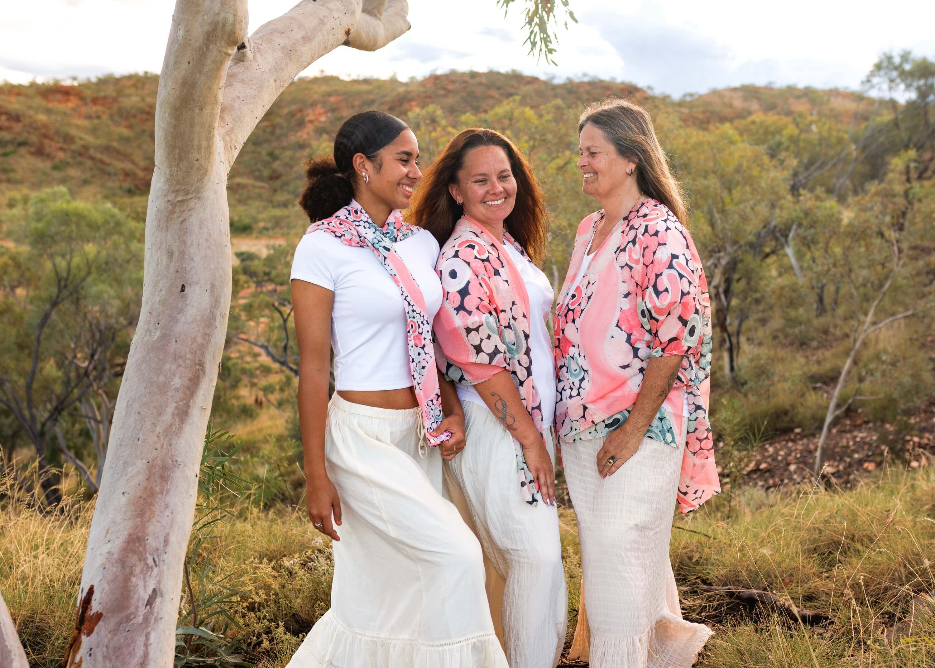 three ladies wearing pink clothing with artwork by Shanai Kelllett