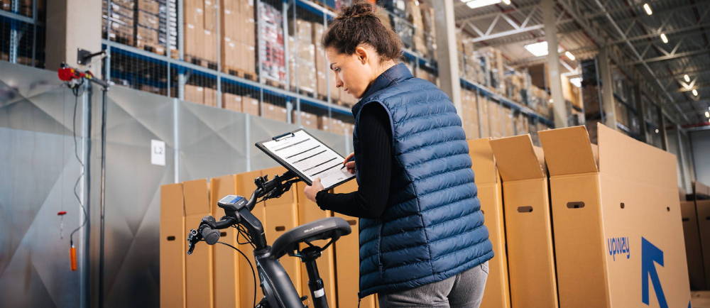 a mechanic going over a checklist and inspecting an electric city bike at an upway center