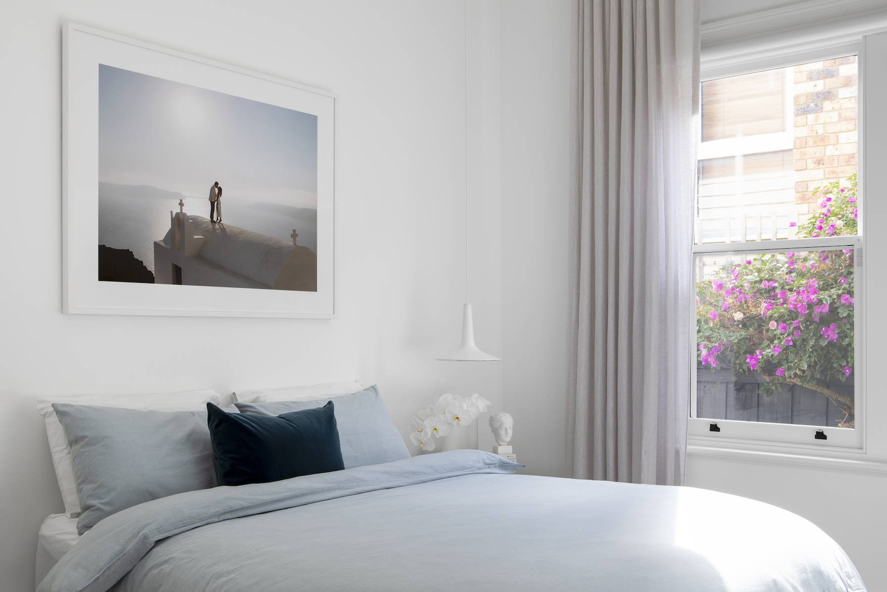 Wedding photography framed and hanging above a bed, the image shows flowering bougainvillea outside the window 