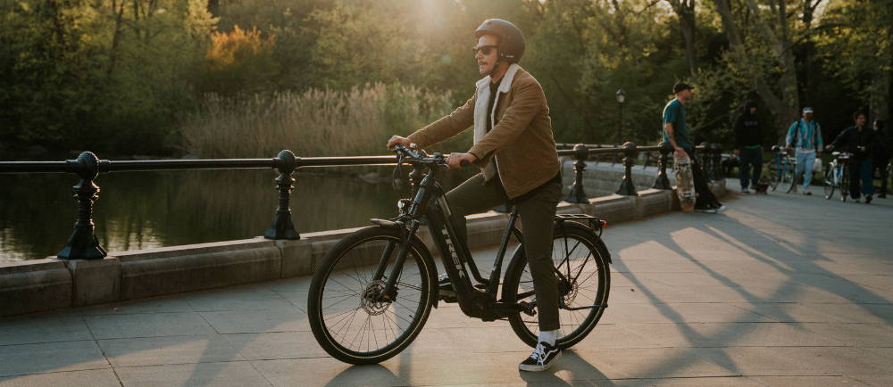 A male sitting on a Trek city bike in a park