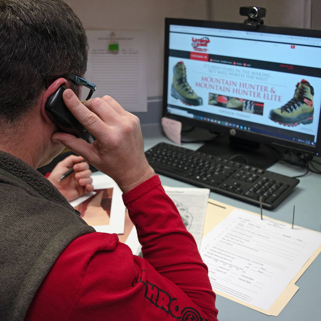 a man holding a phone to his ear and looking at a computer screen