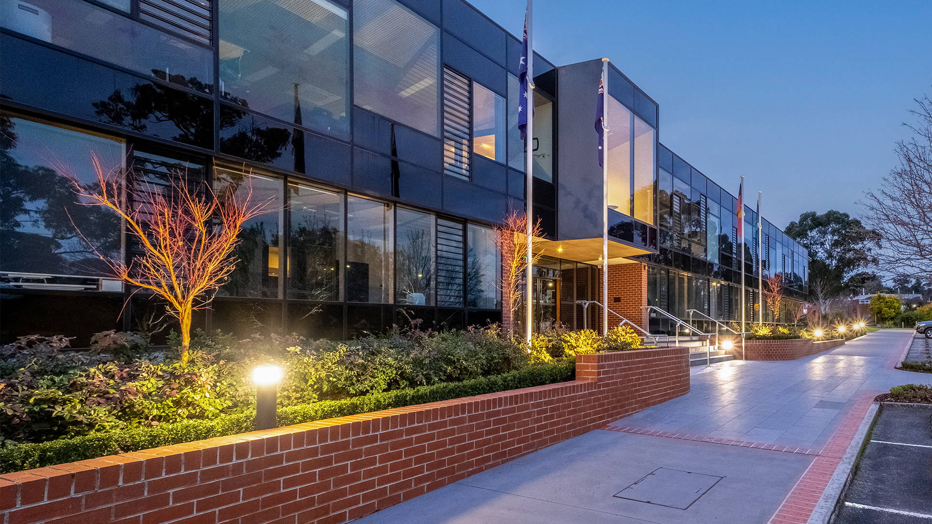 Night time illuminated view of a Havit Commercial Bollard LED Light situated in one of the garden beds of Luther College