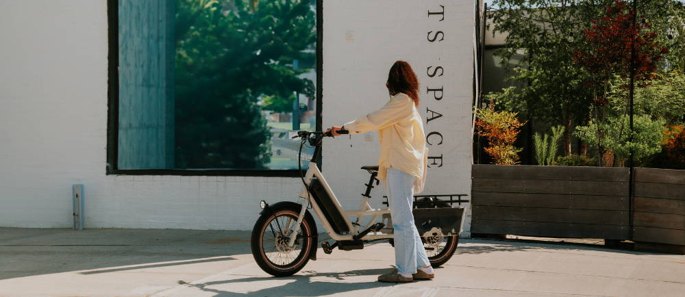 A woman walking an electric cargo bike