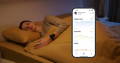 Woman wearing Checkme O2 Max during sleep with mobile app showing oxygen level, pulse rate, and motion trends