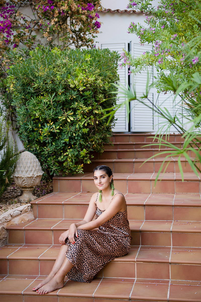 Lauren Mills sits on a stairs to their Ibiza home whilst wearing YOLKE's Classic Leopard Silk Slip