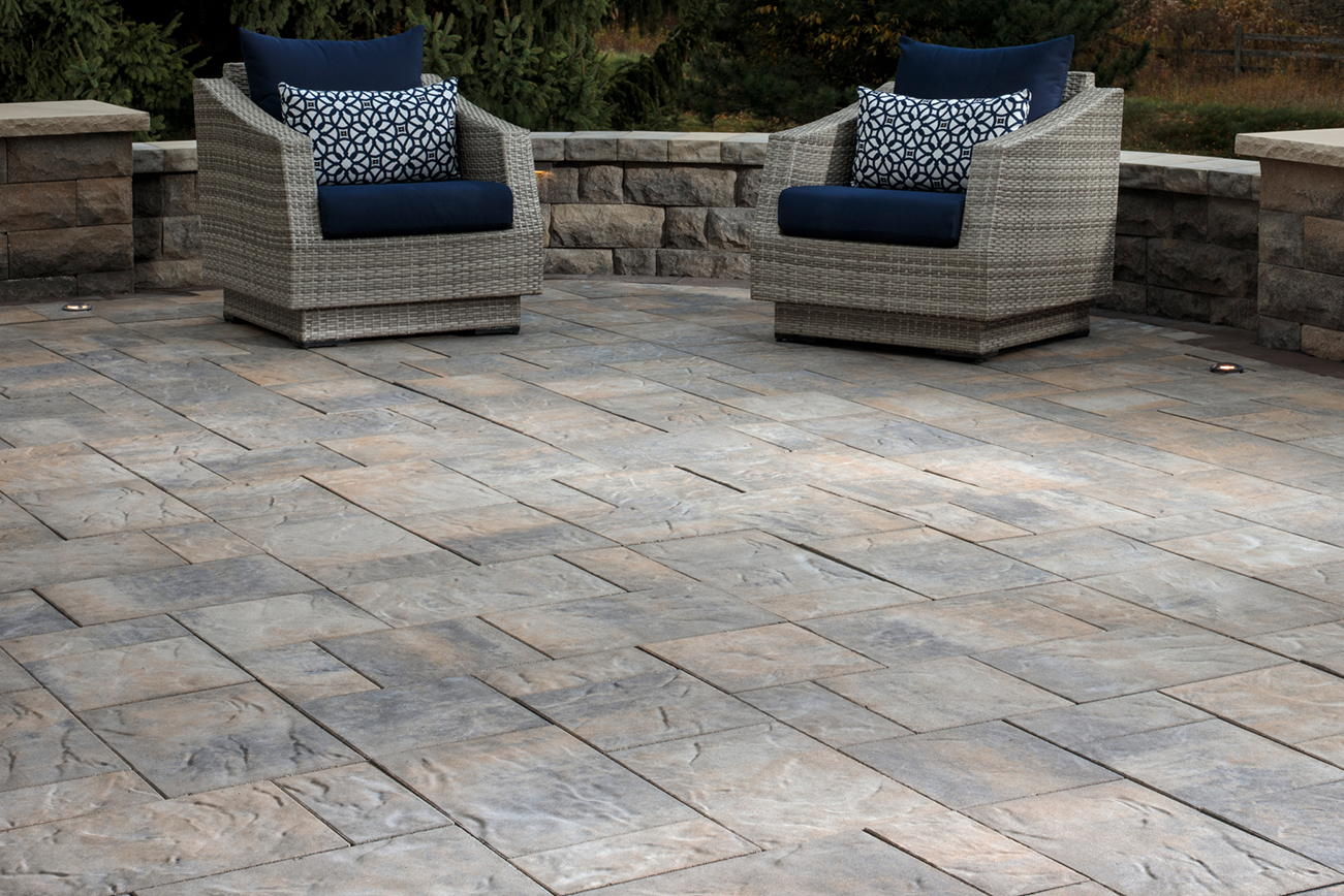 Large patio made with Origin Large Paver Set with a retaining wall and two patio chairs.