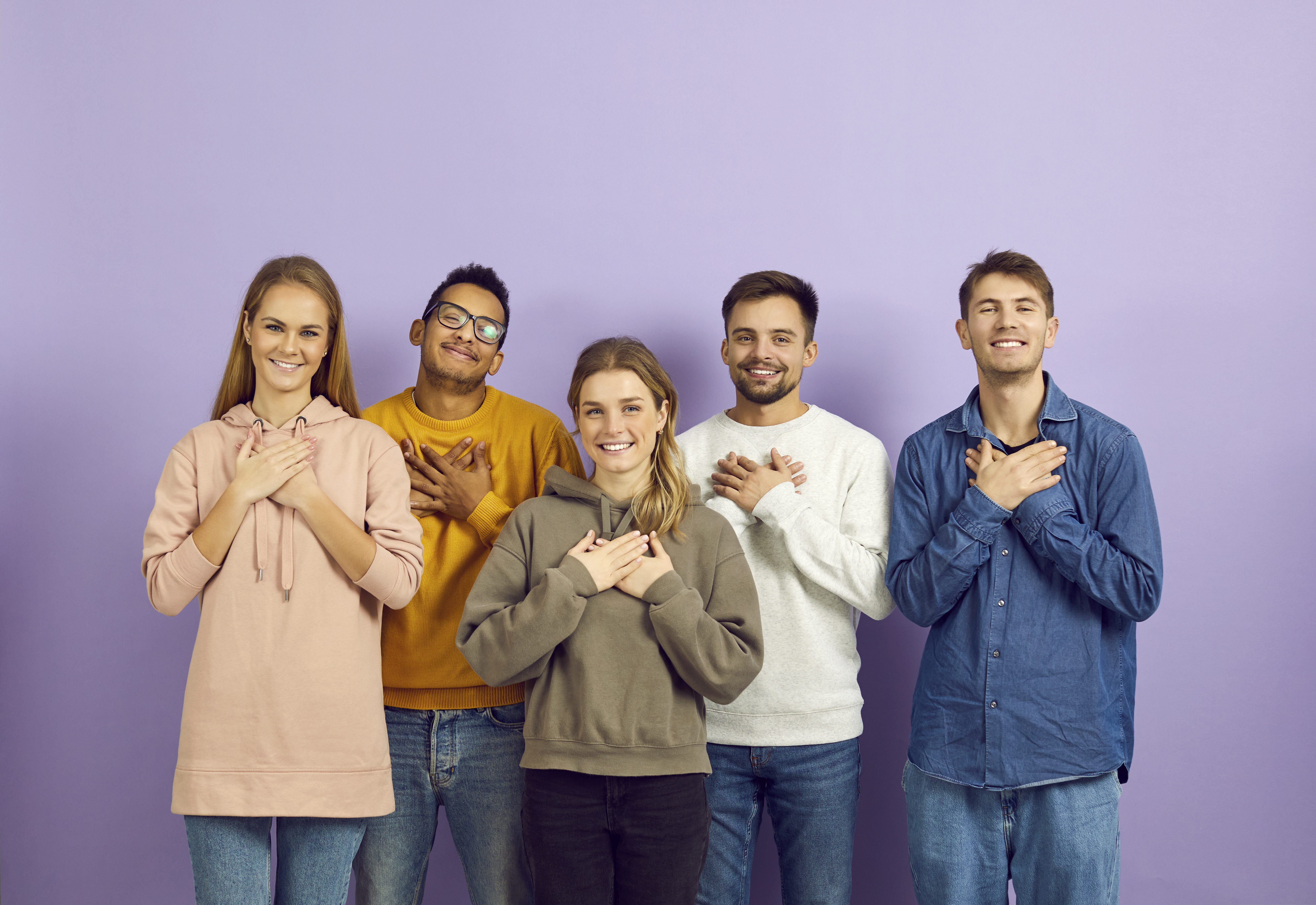 Happy people holding hands on their chests to express their gratitude and appreciation