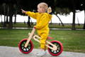 Cute girl in yellow clothes riding a wooden bike for children.