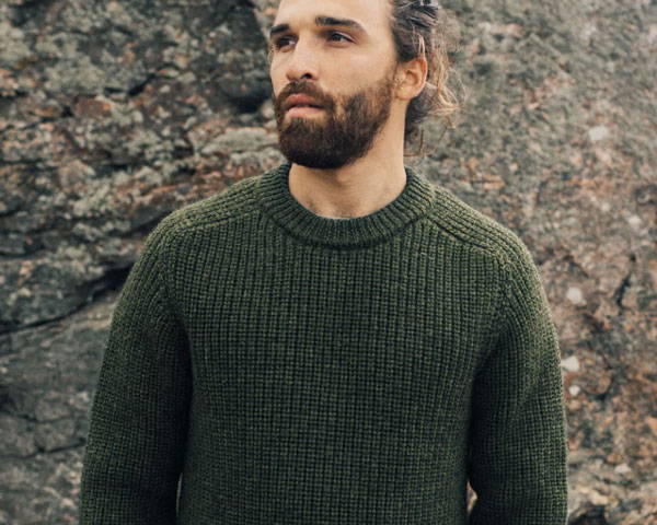 Man wearing khaki green British Wool jumper from sustainable men's clothing brand Finisterre based in Cornwall, UK