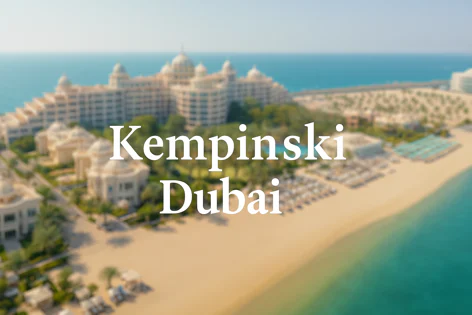 Scenic aerial shot showing the luxurious Kempinski hotel resort complex along the white sandy beach of Dubai, with the sea visible.