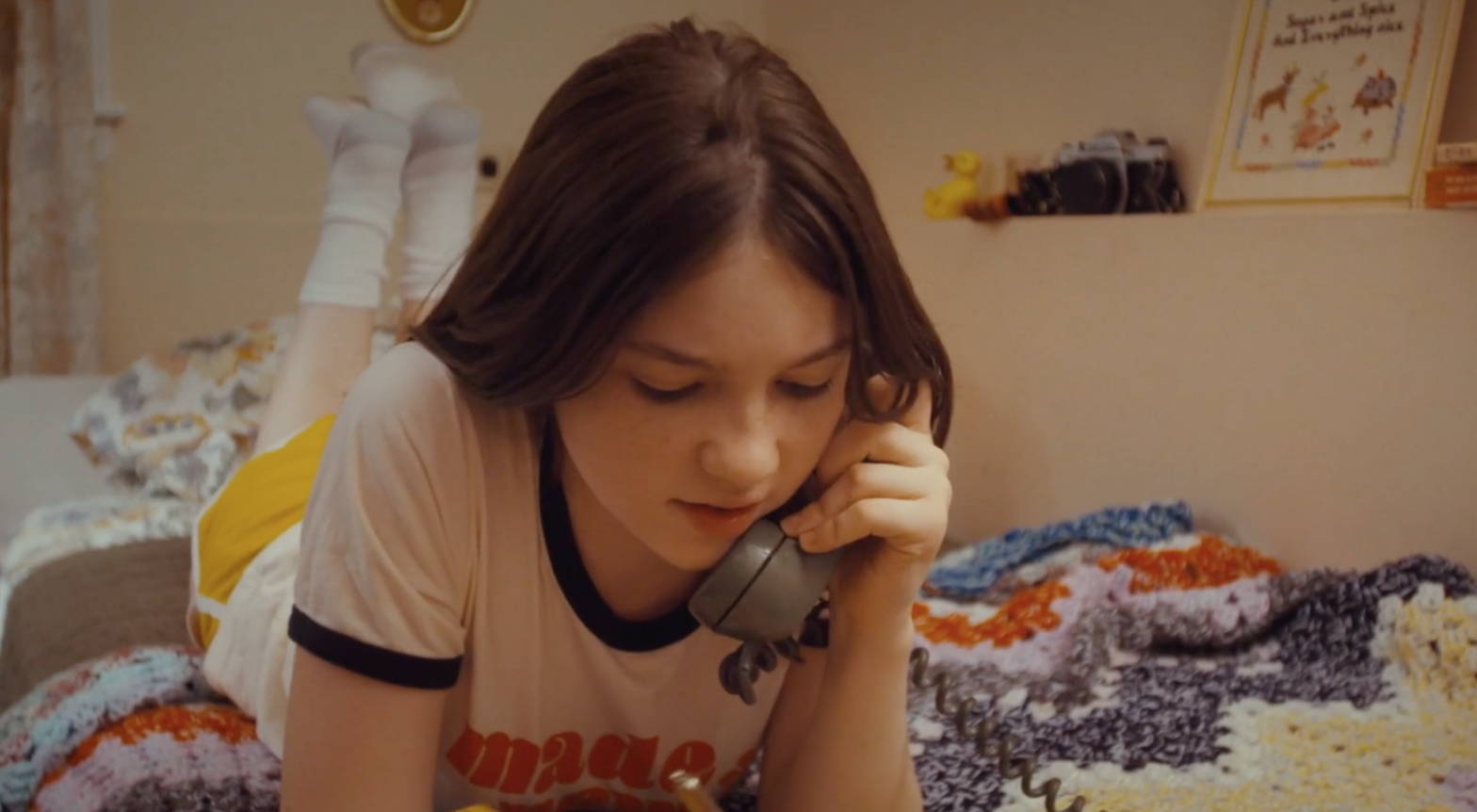 Girl laying on her bed, talking on a 1970s phone