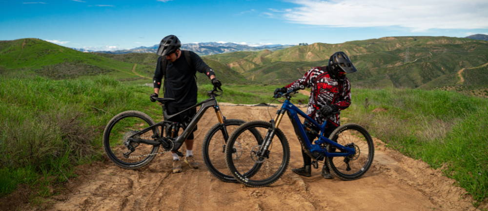 two men standing next to their electric mountain bikes above Los Angeles