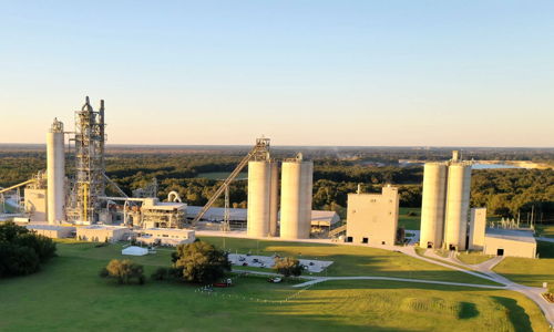 Industrial complex with silos in a green landscape; evokes productivity, stability, and tension between industry and nature.