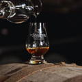 Verre de dégustation de Whisky Glencairn posé sur un fût en bois à la distillerie Glen Ord dans le nord-ouest des Highlands d'Ecosse