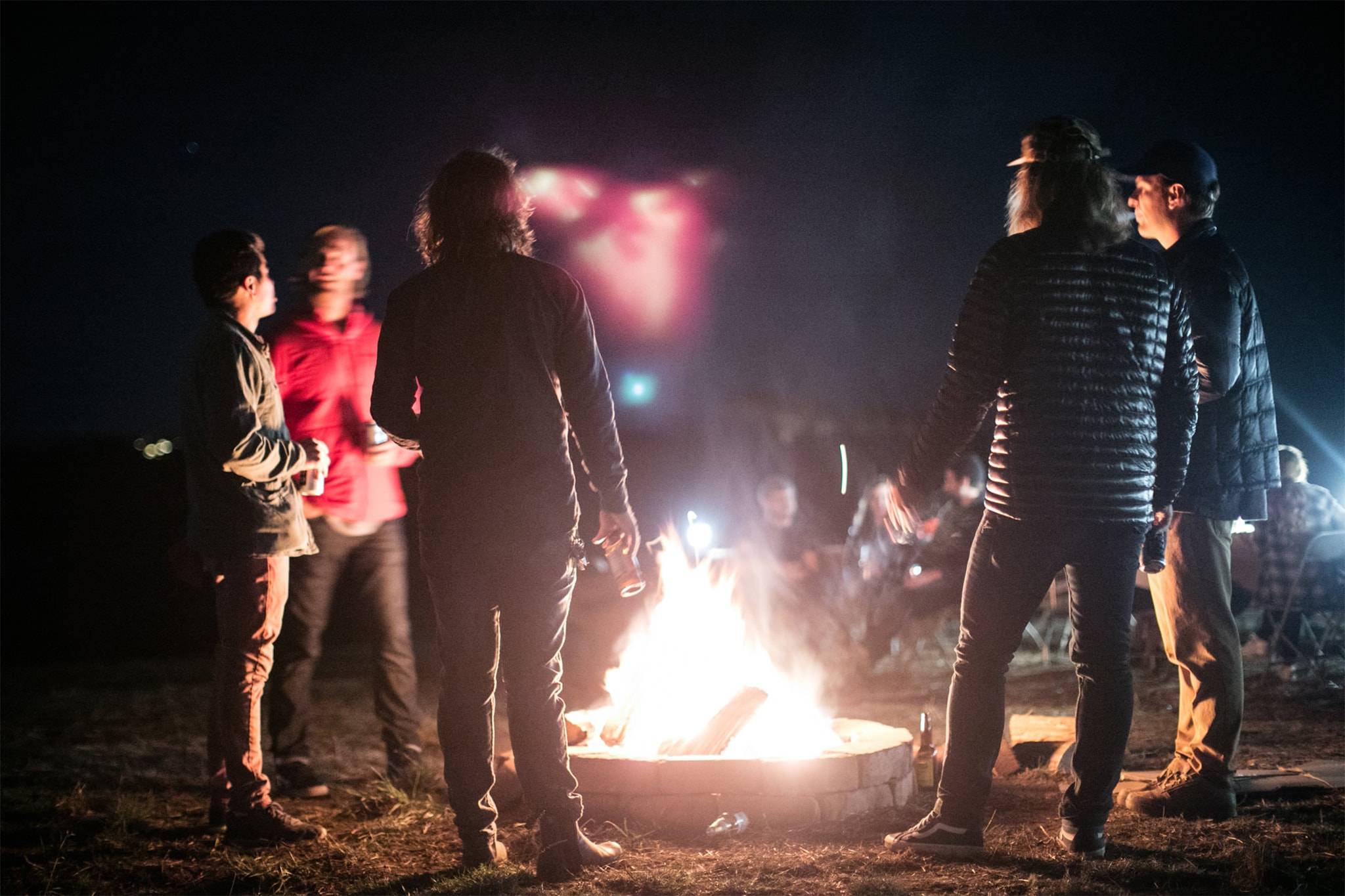 Five people standing around a campfire