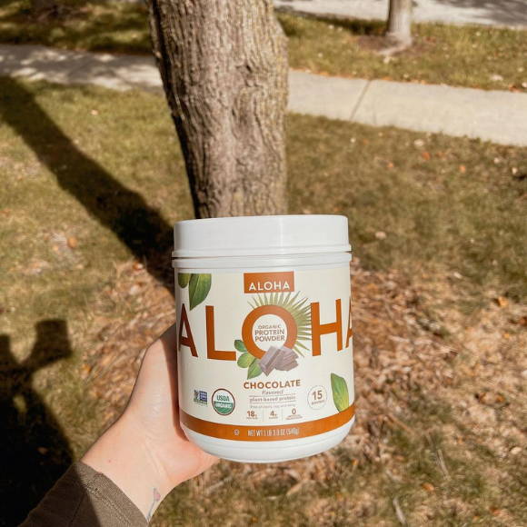 athlete shows his bottle of ALOHA protein outside the house