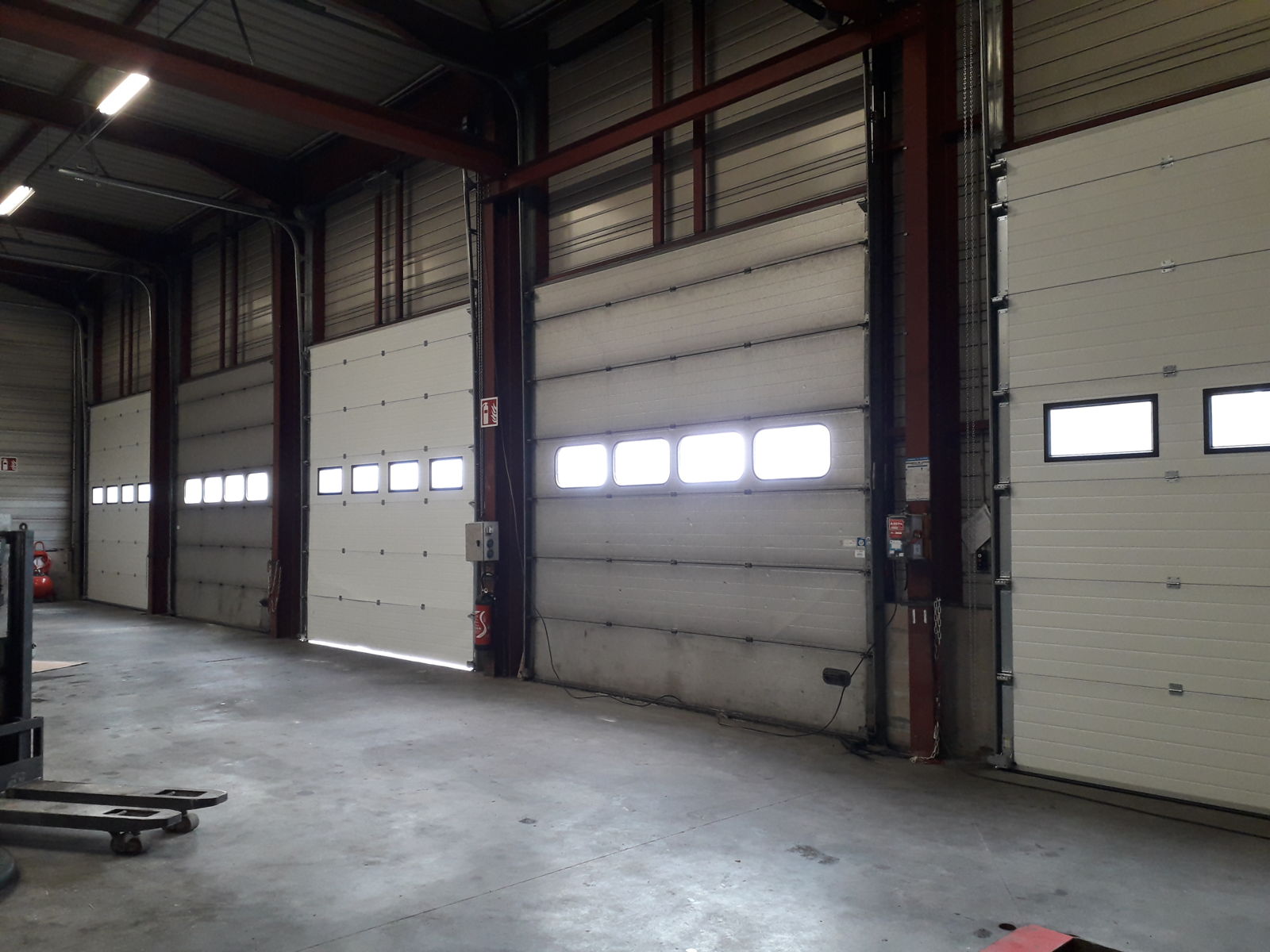 Portes sectionnelles industrielles à hublots dans un entrepôt logistique