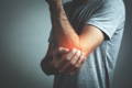 Man holding achy elbow - joint pain reduced with use of collagen