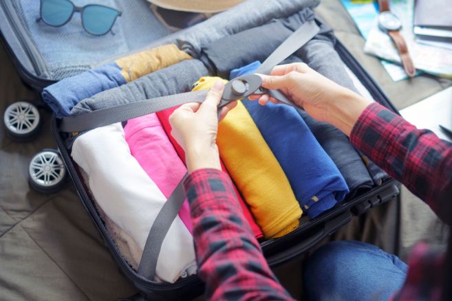Woman pack clothes in suitcase bag on bed, prepare for new journey and travel to long weekend trip.