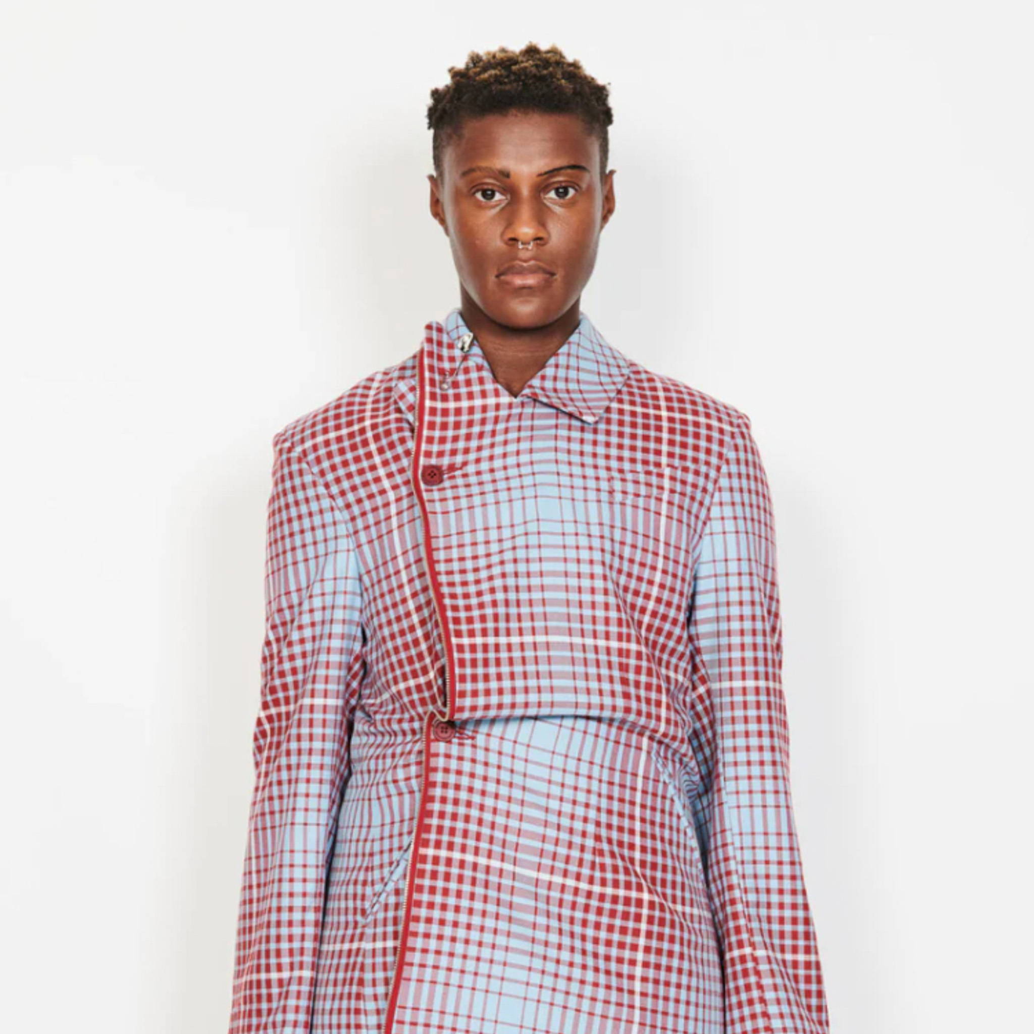 Model Kenya stands against a white background wearing a red and white patterned trench coat