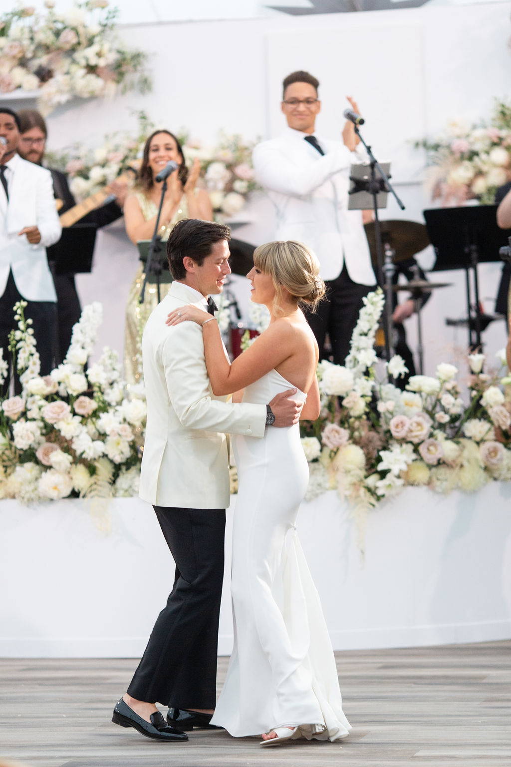 Newlyweds dancing in front of floral covered stage