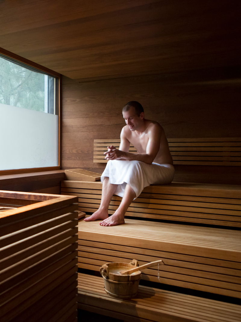 Mann mit Handtuch sitzt in der Sauna