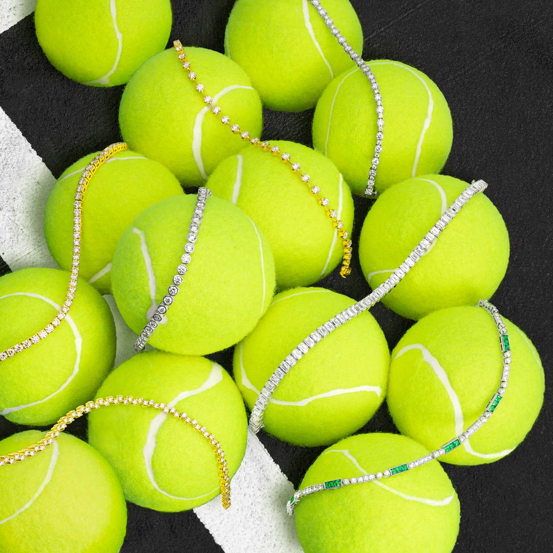 Tennis balls with assorted tennis bracelets laying on top of them