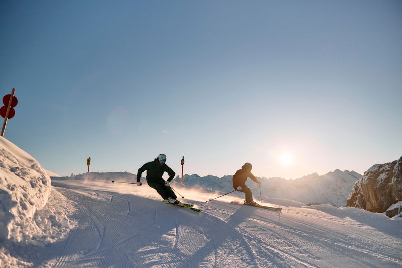 Skifahrer auf einer Piste im Kleinwalsertal bei Sonnenuntergang nahe Mittelberg.