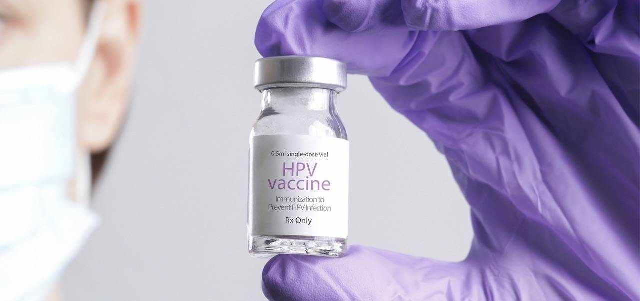 Hand hält HPV Impfstoff in die Kamera