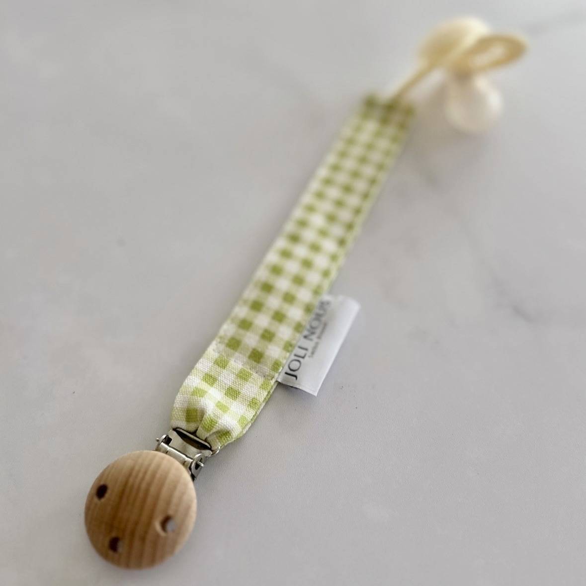 Attache-tétine fraises rouge blanc élégant de la marque suisse 'Joli Nous', un accessoire premium pour bébé, alliant design raffiné et qualité exceptionnelle