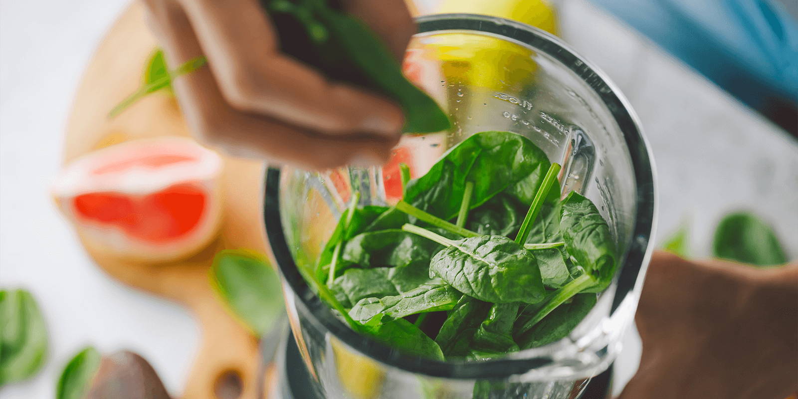 A blender pitcher full of spinach