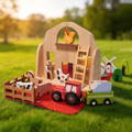 Wooden travel farm playset with a red barn, farm animals, ladder, windmill, and toy tractor on grass.