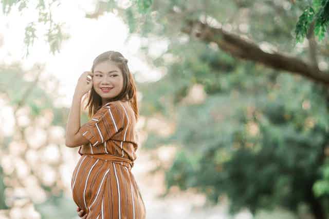 Pregnant woman smiling in brown dress