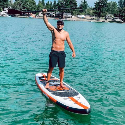 Customer stand up paddleboarding in Canada lake and brave hand up his paddle