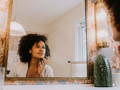 woman looking at her face in the mirror
