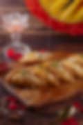 A plate of golden sweets made with almonds and pistachios, drizzled with honey, presented on a wooden board.