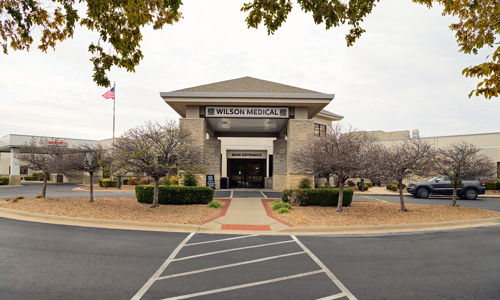 A well-maintained building labeled "WILSON," surrounded by neat landscaping under an overcast sky, conveys professionalism and stability.