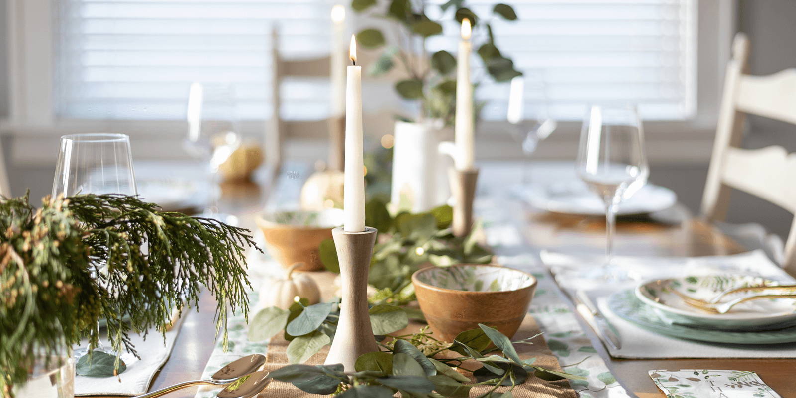 Table set with greenery, candles, and dishware.