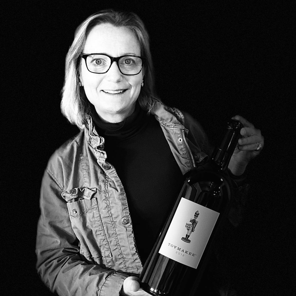 Black and white image of Toymaker Cellars head winemaker, Martha McClellan, holding a magnum wine bottle of 2012 Toymaker Cabernet Sauvignon. Wines by Martha McClellan, Martha McClellan, Martha McClellan, Martha McClellan, Martha McClellan, Martha McClellan, Martha McClellan, Martha McClellan, Martha McClellan, Martha McClellan, Martha McClellan, Martha McClellan, Martha McClellan, Martha McClellan, Martha McClellan