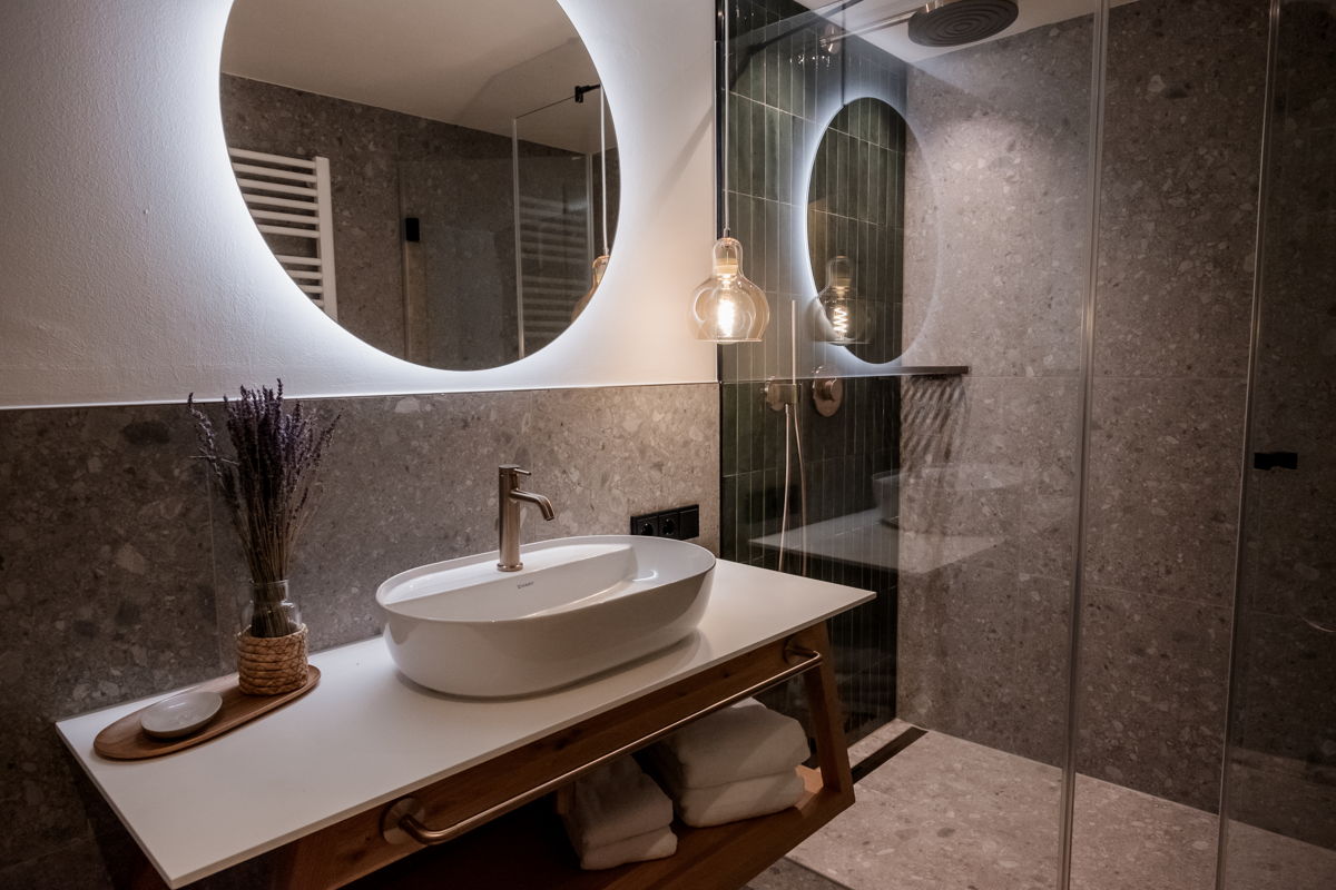 Badezimmer mit Waschbecken und rundem Spiegel im Apartment Waldgeflüster.