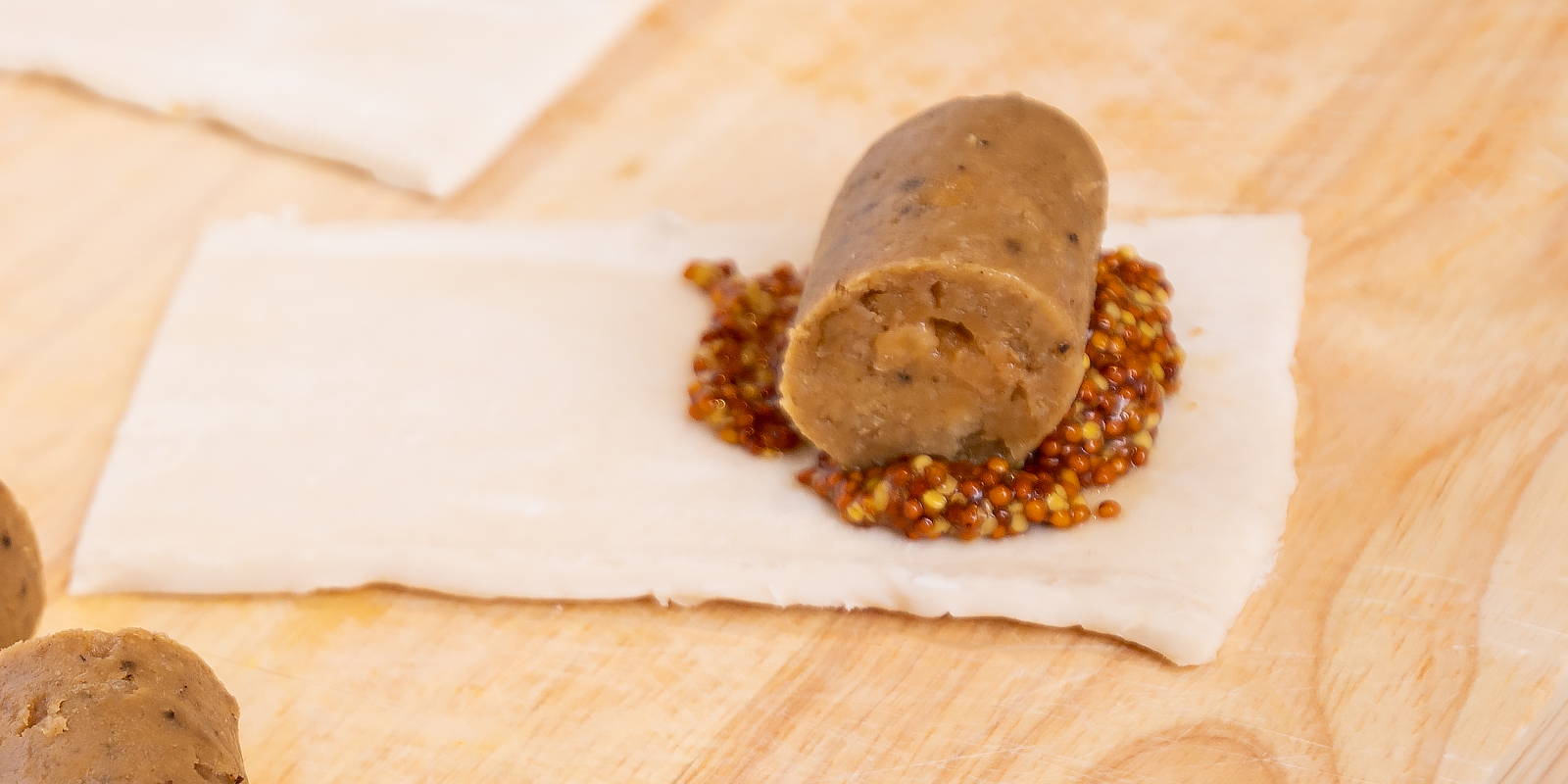 Plant-based meatless sausage, rolled in mustard and vegan pastry for Oktoberfest holiday grazing board.