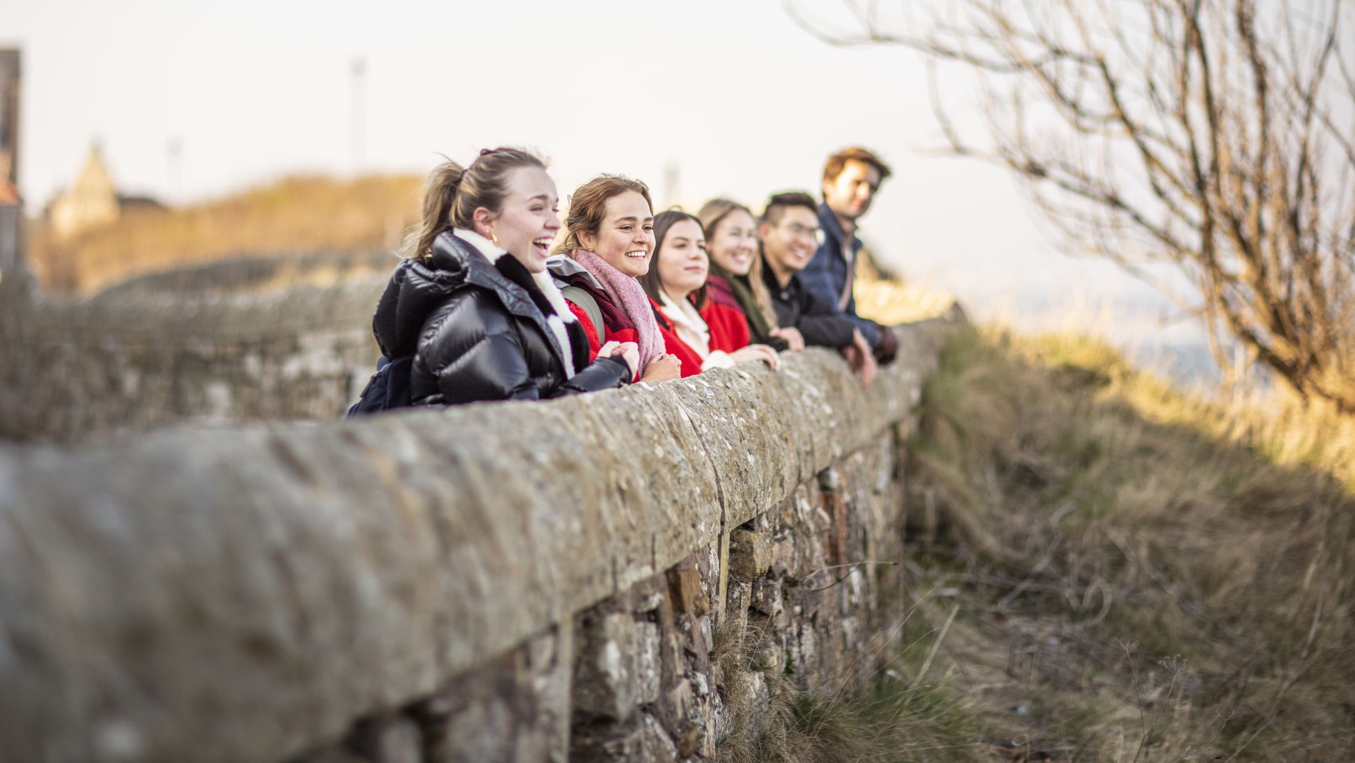 Students leaning against a wall looking at the view