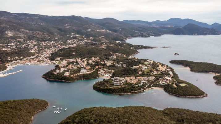 The surrounding lush green hills provide a striking backdrop to the charming village of Syvota