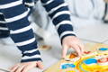 The little boy's hands move a wooden piece from the Montessori wooden puzzle toy. 