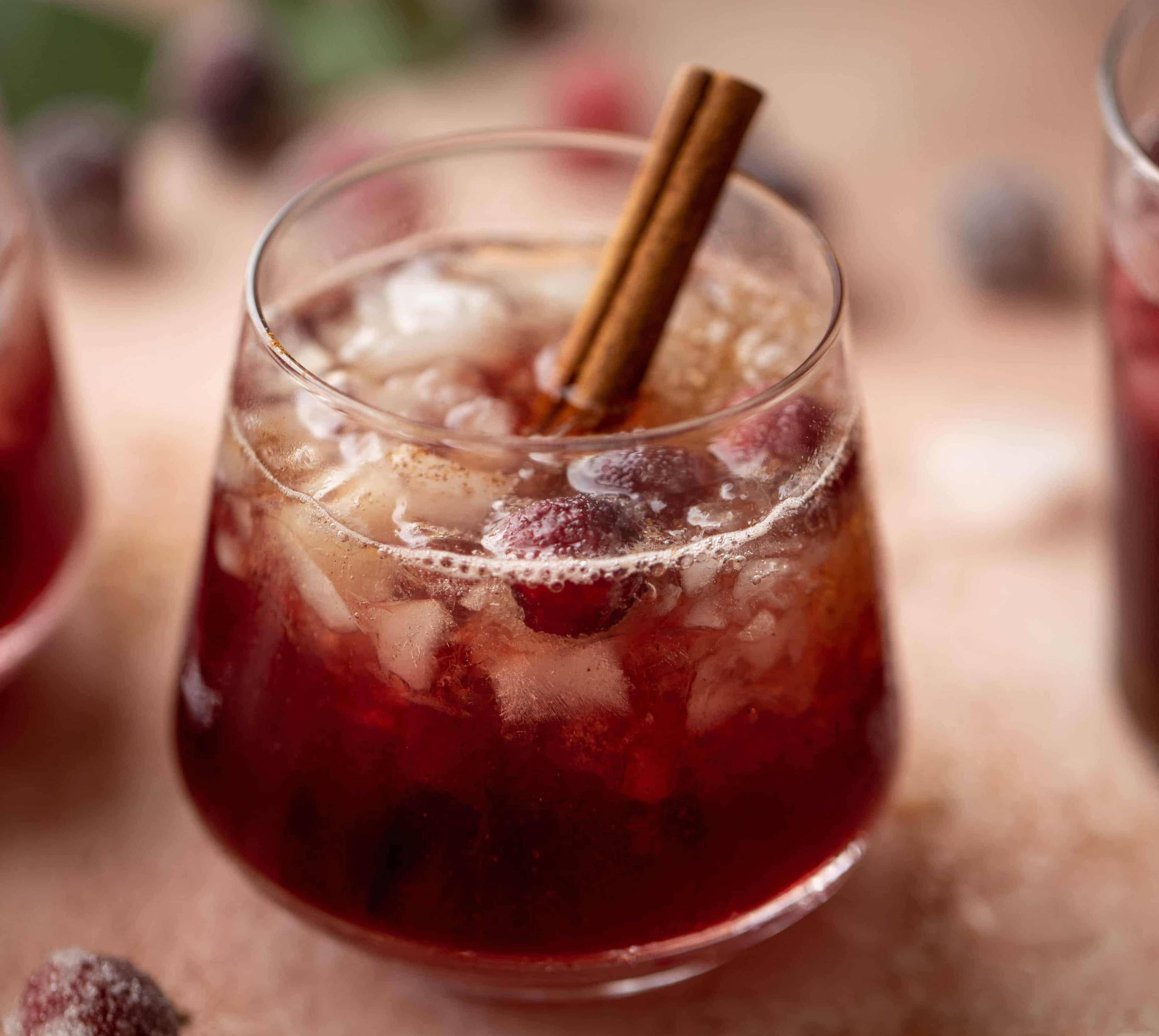 clear cup with berries and cinnamon stick in iced drink