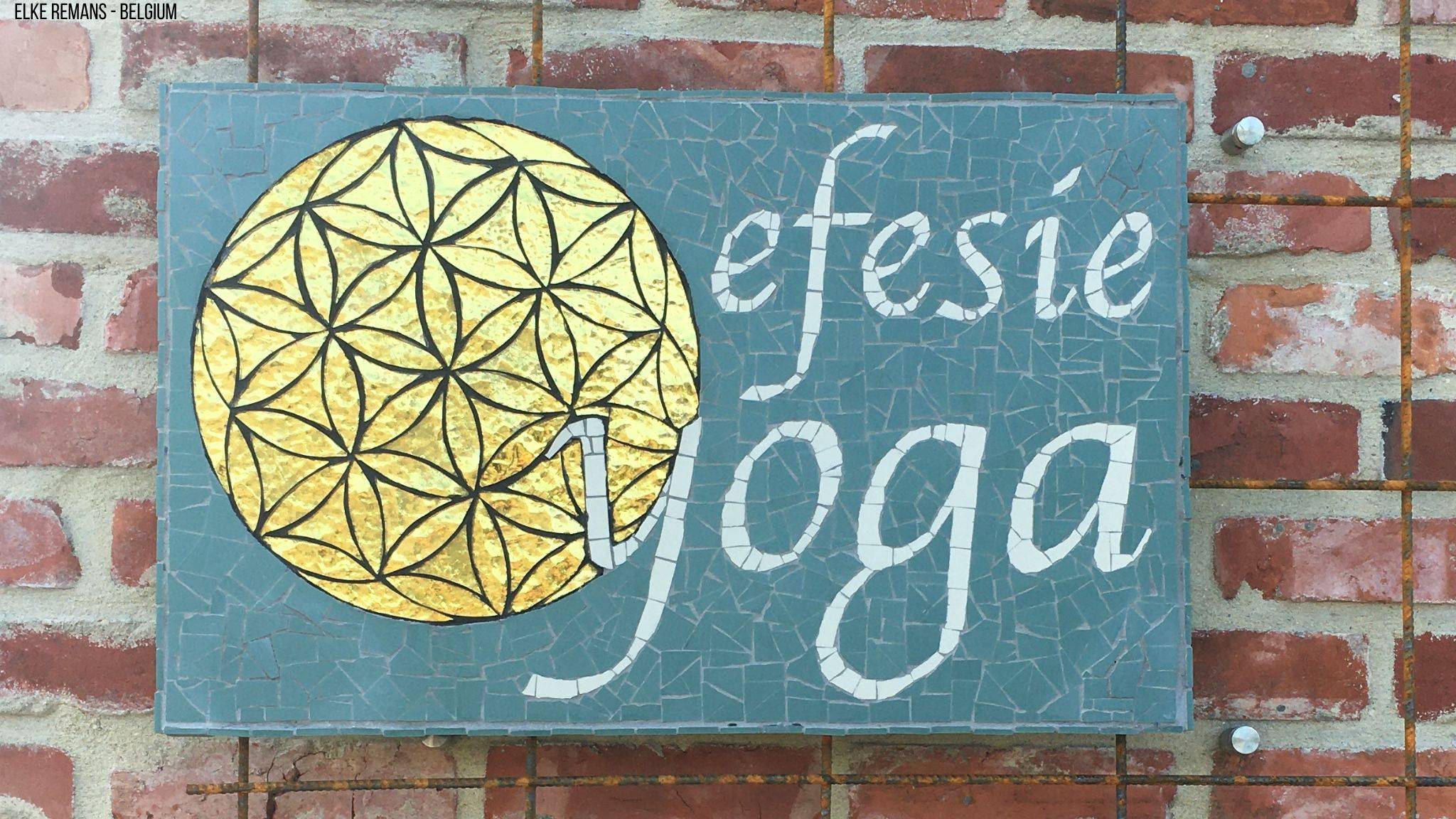 Het logo van Efesie Yoga gemaakt in mozaiek. Op het logo staat de ‘The Flower of Life’ gemaakt met gouden spiegel. De letters zijn gemaakt in witte mozaiektegels van Winckelmans en de achtergrond met groene mozaiektegels van Winckelmans.