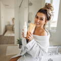 woman sitting by a shower holding ewc skincare products