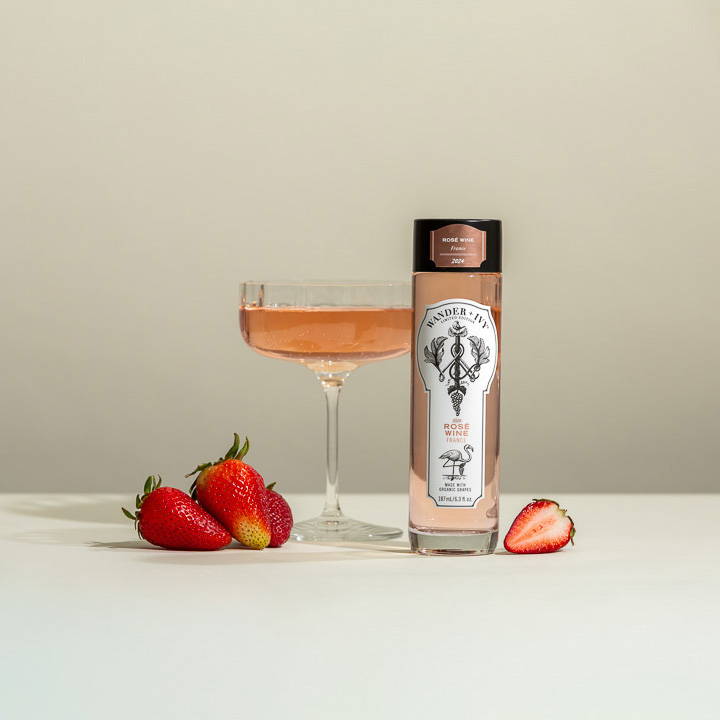 A single-serve bottle of Rosé with sliced apples and strawberries