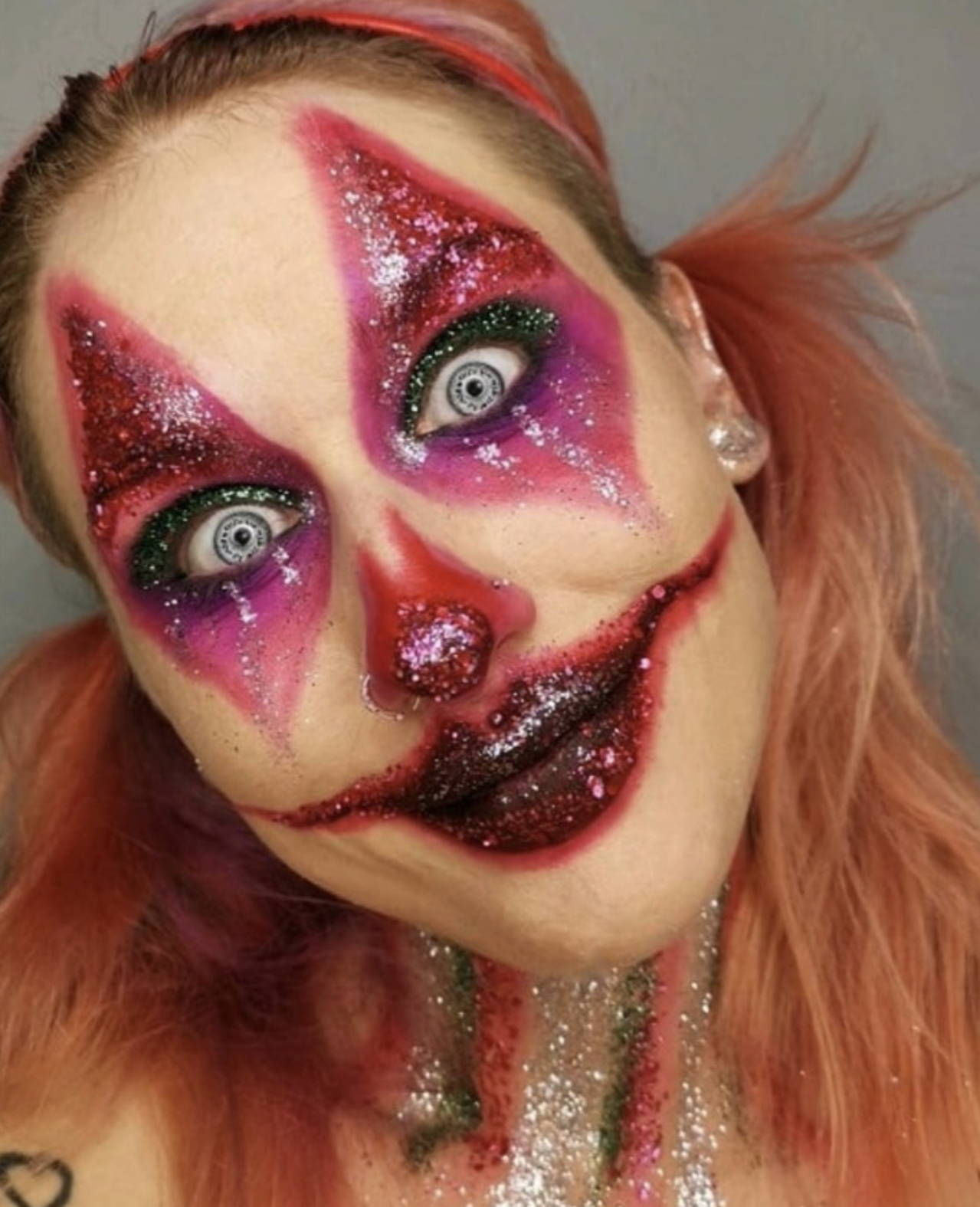 A scary clown halloween makeup look with wide eyes and glitter covering the face
