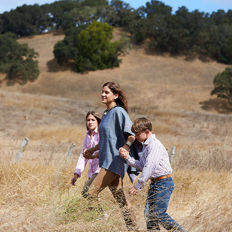 Elizabeth and her children walk across an open field on a sunny day.